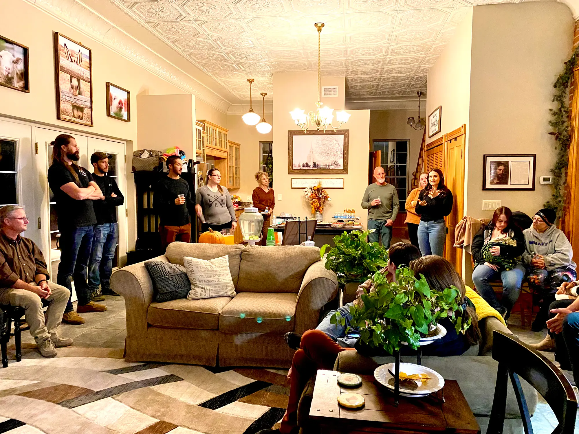 A wide view of the living room during a gathering, with guests spread across the seating