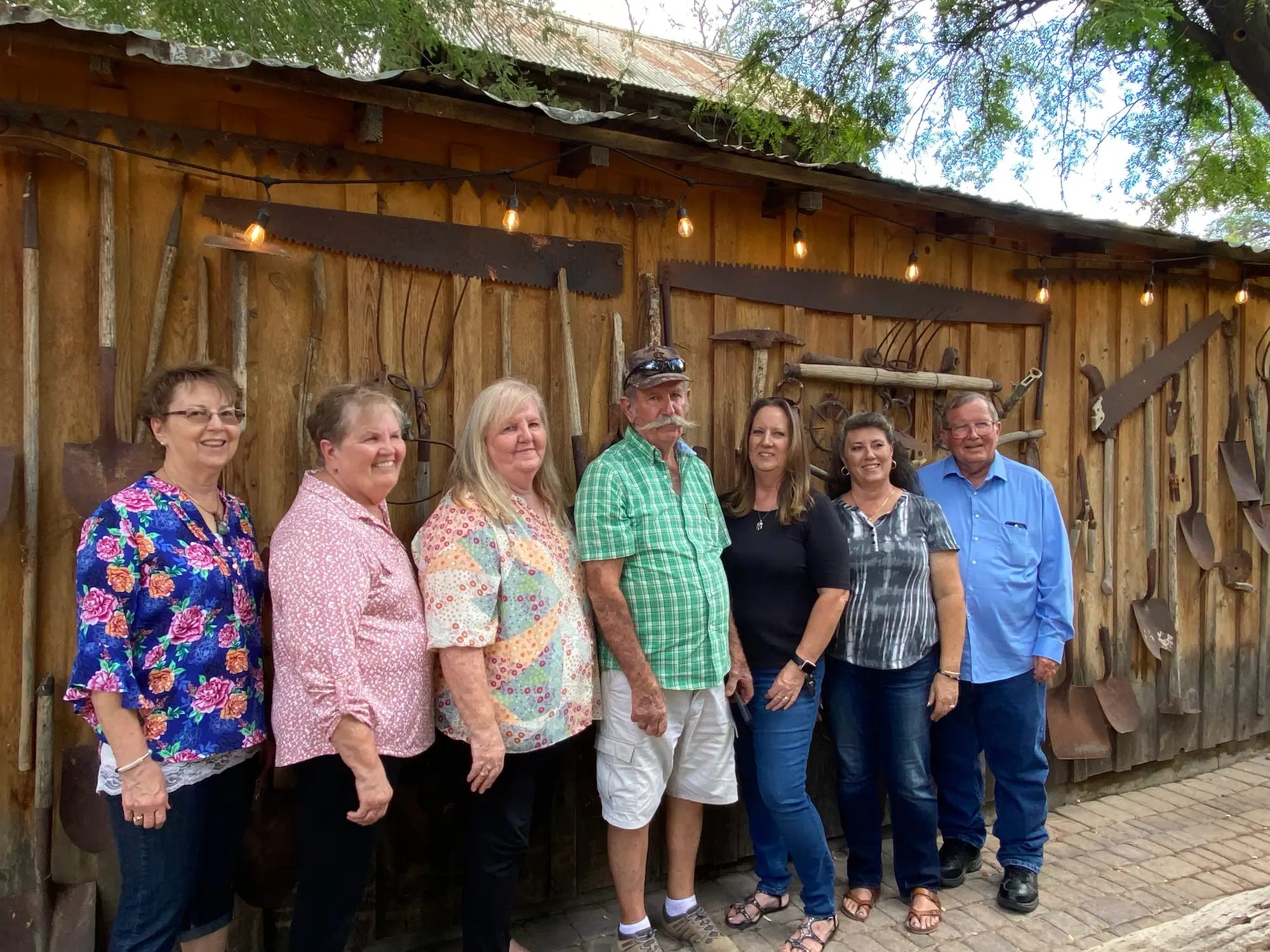 A group portrait at the barn beneath strung lights